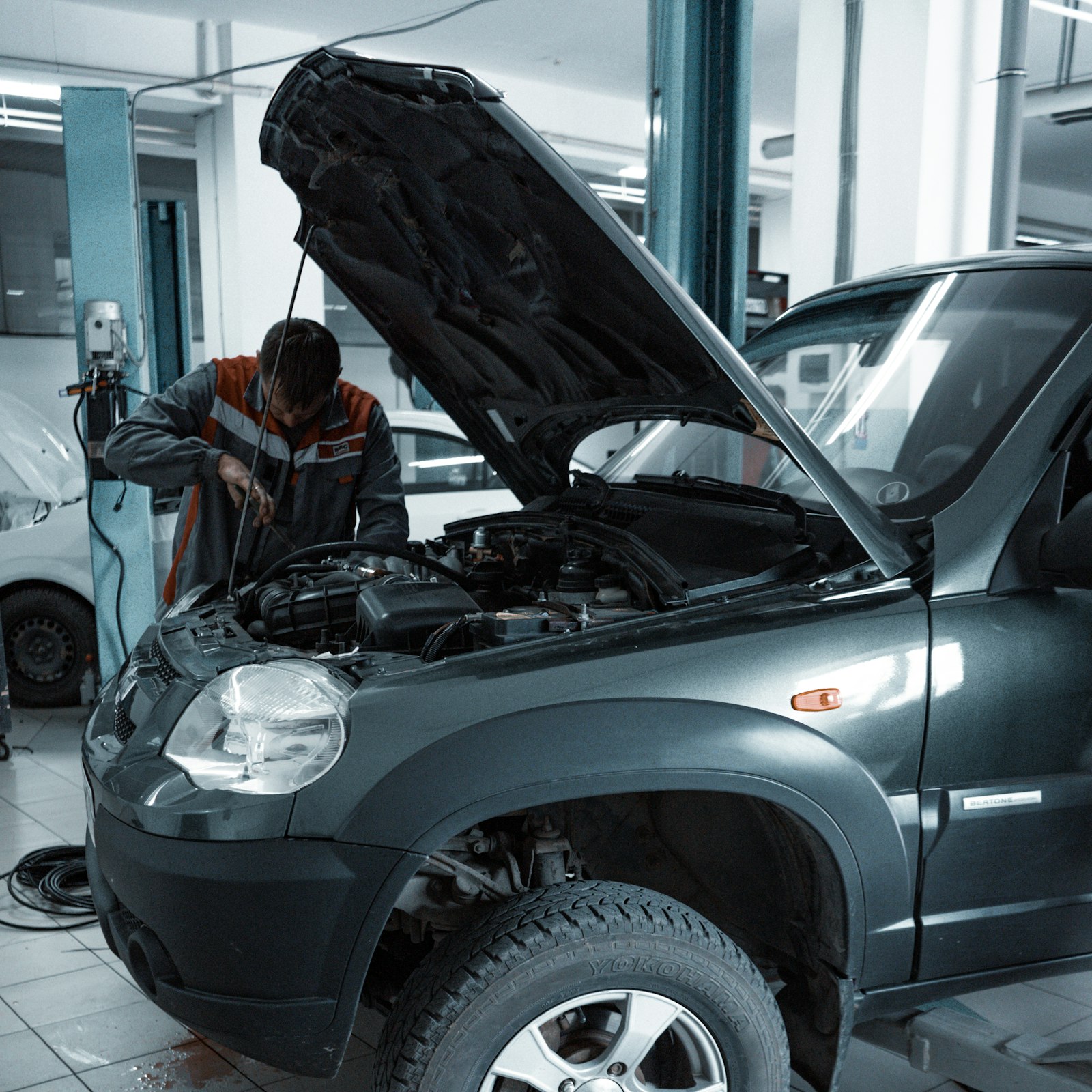 Mecânico trabalhando sob um carro em uma oficina moderna
